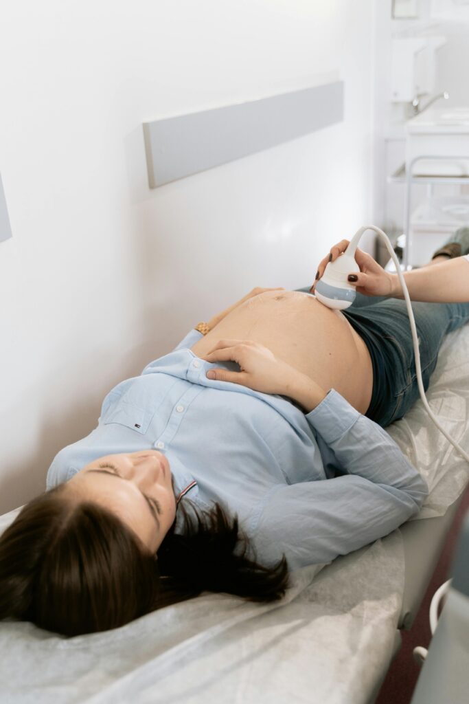 Pregnant woman receiving ultrasound in medical clinic for prenatal care.